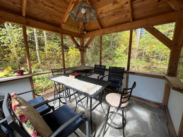 sunroom / solarium with vaulted ceiling with beams, wooden ceiling, and a wealth of natural light