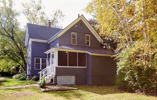 back of house featuring a sunroom and a lawn