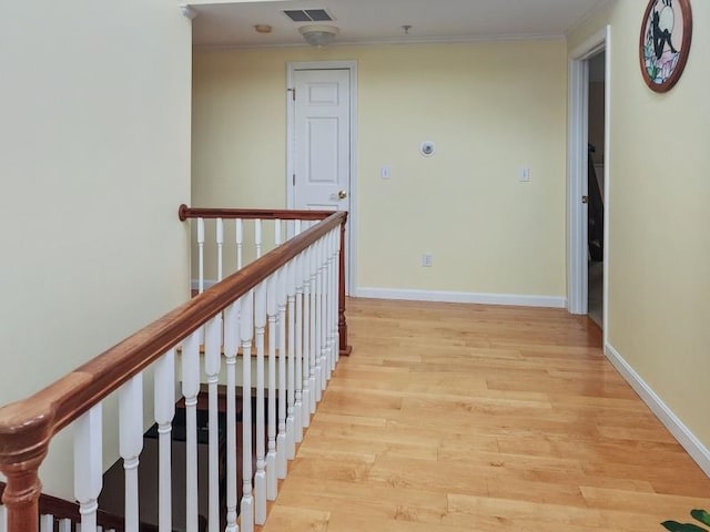 hallway with ornamental molding and light hardwood / wood-style floors