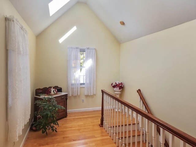 hallway with light hardwood / wood-style floors and vaulted ceiling with skylight