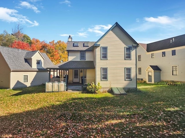 rear view of house featuring a yard and covered porch