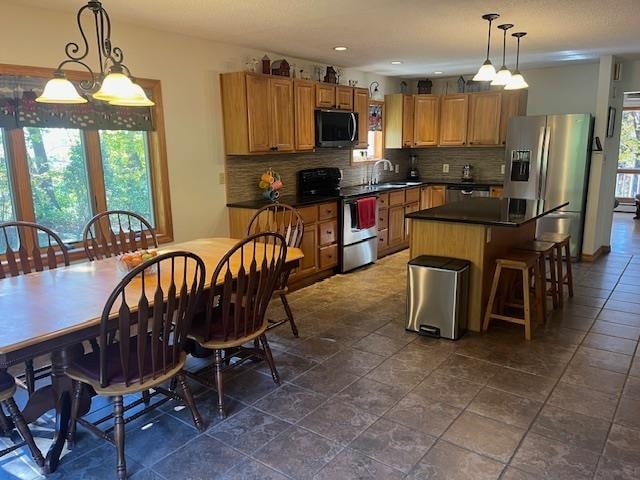 kitchen featuring pendant lighting, appliances with stainless steel finishes, a center island, and a wealth of natural light