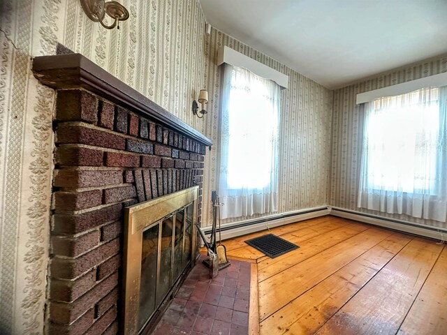 unfurnished living room with wood-type flooring, wallpapered walls, plenty of natural light, and a fireplace