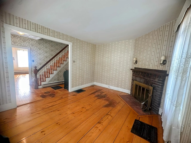 room details featuring a brick fireplace, wallpapered walls, and a baseboard radiator