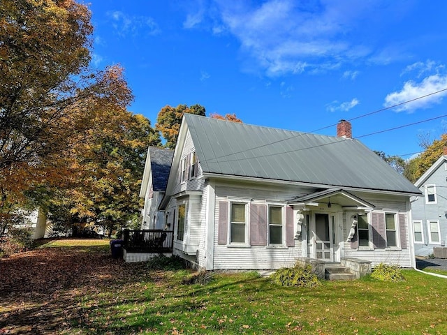 view of front of house featuring a front lawn, a chimney, and metal roof