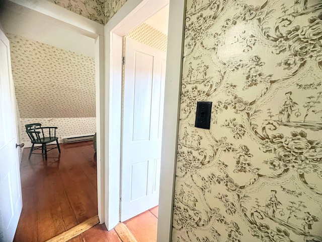 interior space with wallpapered walls, wood finished floors, lofted ceiling, and a baseboard radiator