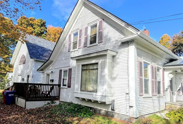 view of side of home with a wooden deck and a chimney
