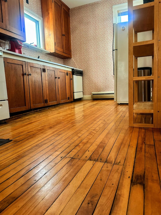 washroom featuring separate washer and dryer, a baseboard radiator, hardwood / wood-style floors, and laundry area