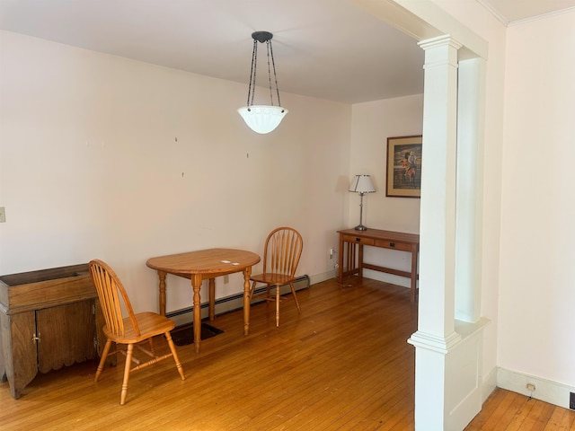 unfurnished living room featuring decorative columns, a baseboard heating unit, and hardwood / wood-style floors