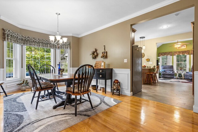 dining space featuring ceiling fan with notable chandelier, crown molding, and hardwood / wood-style floors