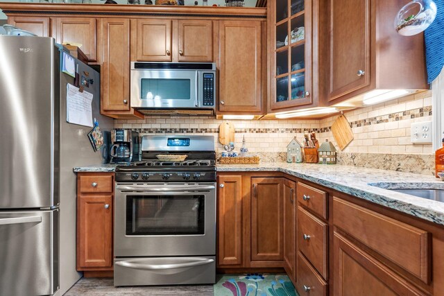 kitchen with light stone countertops, stainless steel appliances, and tasteful backsplash