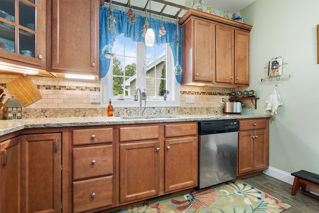 kitchen with pendant lighting, sink, decorative backsplash, light stone countertops, and stainless steel dishwasher