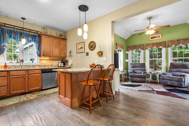 kitchen featuring light wood-type flooring, lofted ceiling, ceiling fan, a breakfast bar area, and dishwasher