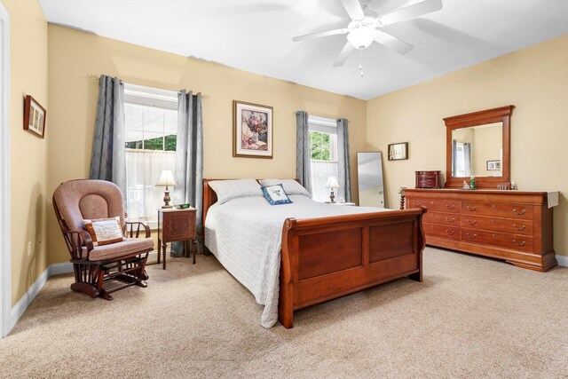 bedroom with multiple windows, ceiling fan, and light colored carpet