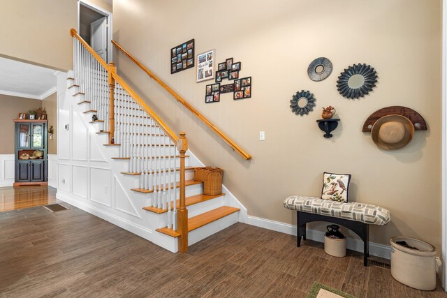 stairway with ornamental molding and hardwood / wood-style flooring