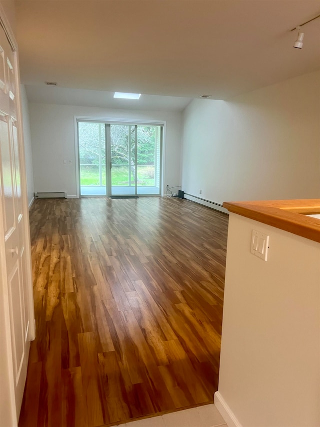 spare room featuring dark wood-type flooring and a baseboard radiator