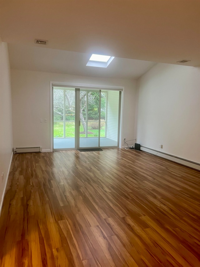 unfurnished room with a skylight, hardwood / wood-style floors, and a baseboard heating unit