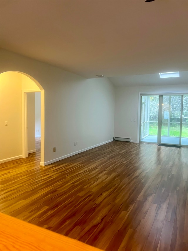 empty room with dark wood-type flooring and a baseboard heating unit