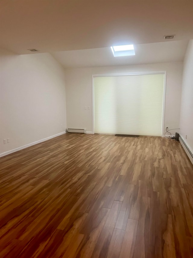 empty room with hardwood / wood-style flooring and a baseboard radiator