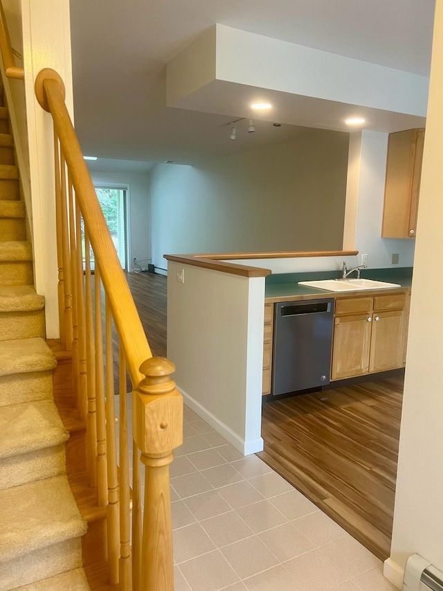 staircase with wood-type flooring, baseboard heating, and sink