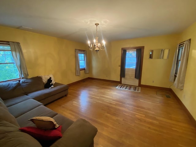 living room featuring an inviting chandelier, plenty of natural light, and hardwood / wood-style flooring