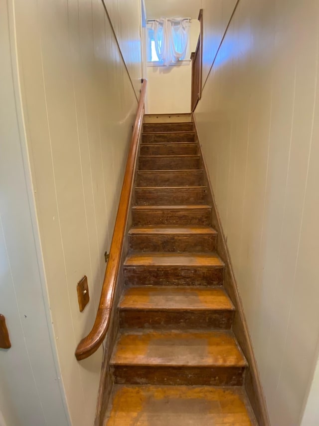 staircase featuring wooden walls