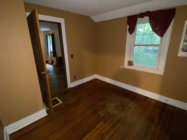 unfurnished room featuring lofted ceiling and dark hardwood / wood-style floors