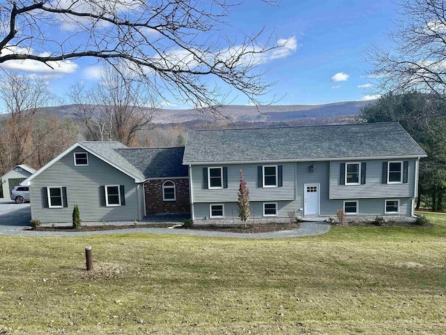 bi-level home with a front lawn, a shingled roof, and a mountain view