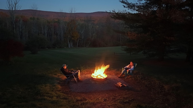 view of yard with a fire pit and a wooded view