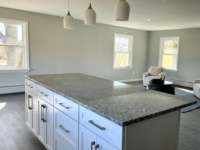 kitchen featuring a center island, a baseboard heating unit, white cabinets, and dark stone counters