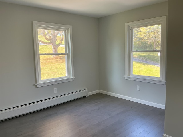 unfurnished room with baseboard heating, a healthy amount of sunlight, and dark wood-type flooring