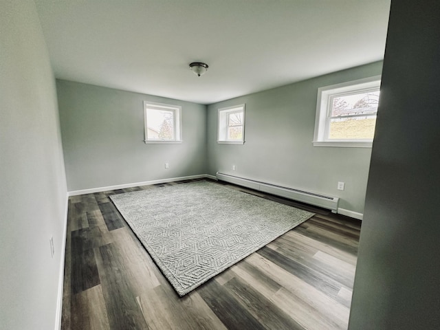 spare room with wood finished floors, baseboard heating, and baseboards