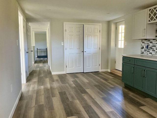 kitchen featuring dark wood-style flooring, green cabinets, light countertops, and baseboards