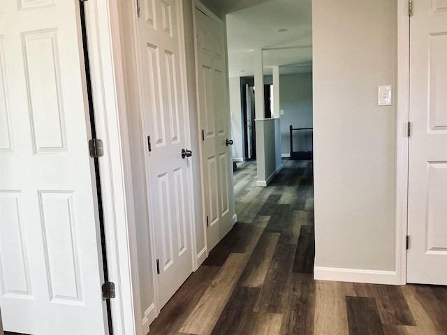 hall featuring dark wood-type flooring and baseboards