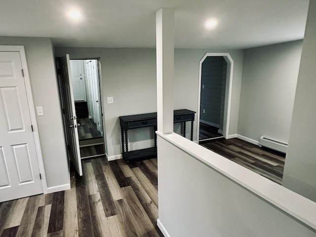 corridor featuring dark wood-style floors, baseboards, and a baseboard radiator