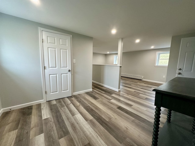 basement with baseboards, recessed lighting, wood finished floors, and a baseboard heating unit