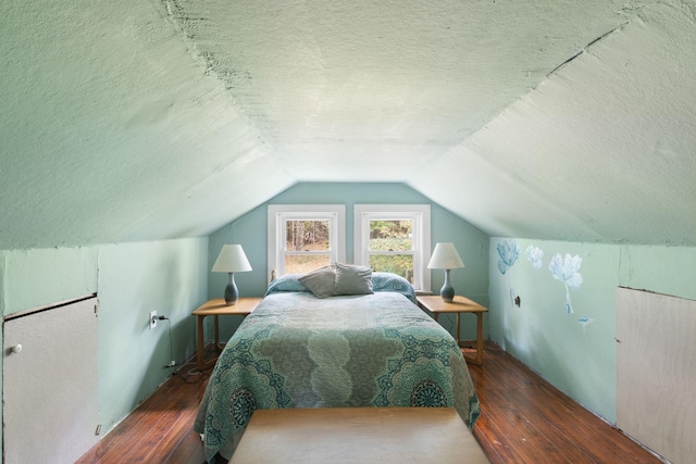 bedroom featuring dark wood-type flooring, a textured ceiling, and vaulted ceiling