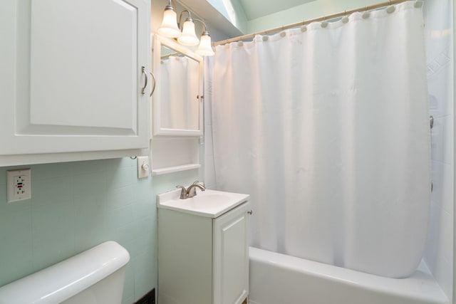 full bathroom featuring toilet, shower / bath combo with shower curtain, tile walls, vaulted ceiling, and vanity