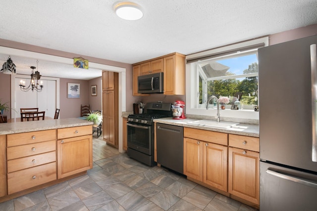 kitchen featuring sink, hanging light fixtures, appliances with stainless steel finishes, and a textured ceiling