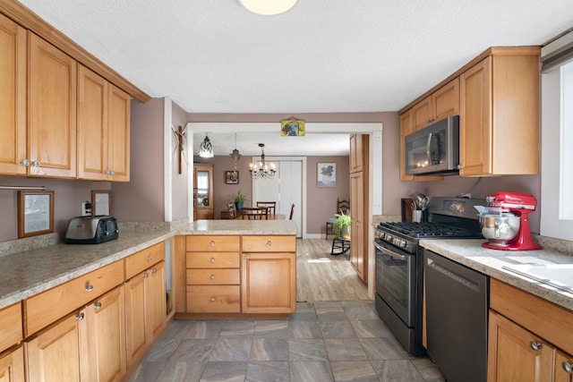 kitchen featuring an inviting chandelier, kitchen peninsula, appliances with stainless steel finishes, decorative light fixtures, and a textured ceiling