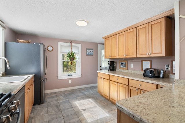 kitchen with stove, sink, light stone countertops, a textured ceiling, and light brown cabinetry