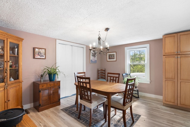 dining area featuring a notable chandelier, a textured ceiling, and light hardwood / wood-style flooring