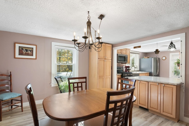 dining space featuring sink, a chandelier, and light wood-type flooring