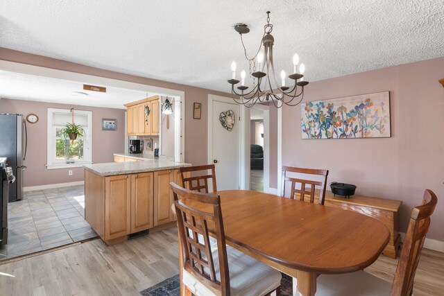 dining room with light hardwood / wood-style floors, a textured ceiling, and a chandelier