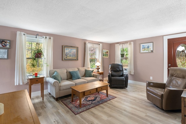 living room with a wealth of natural light, a textured ceiling, and light wood-type flooring