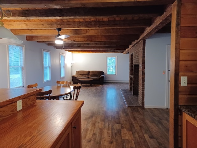 dining space featuring a brick fireplace, ceiling fan, baseboard heating, beam ceiling, and dark hardwood / wood-style flooring