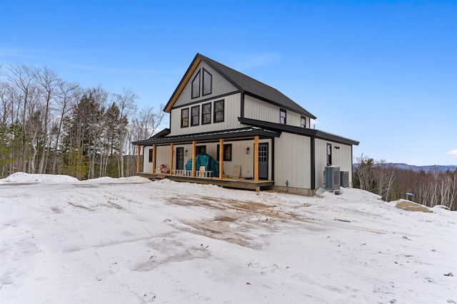 snow covered house featuring covered porch and central AC