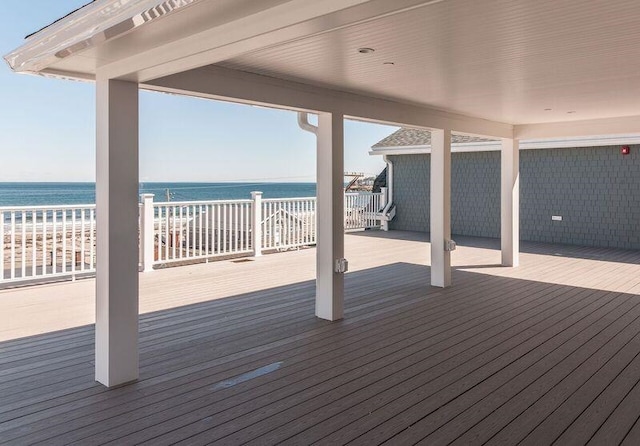 wooden terrace featuring a water view and a beach view