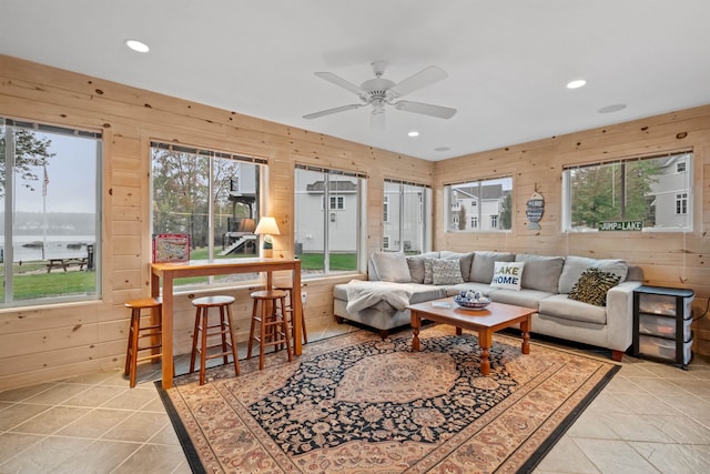 living room with a wealth of natural light, ceiling fan, and wood walls