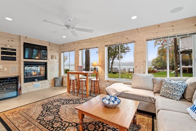 tiled living room featuring ceiling fan, wood walls, and beverage cooler